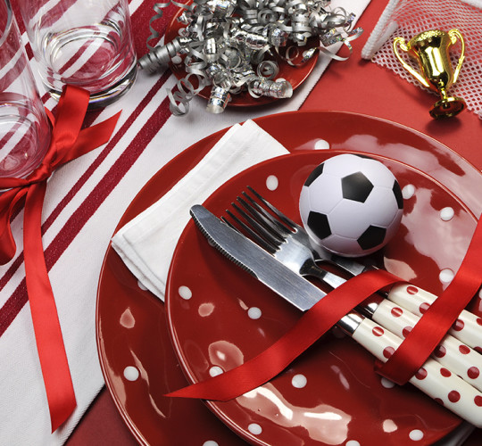 Red polkadotted plates on table with sports decorations