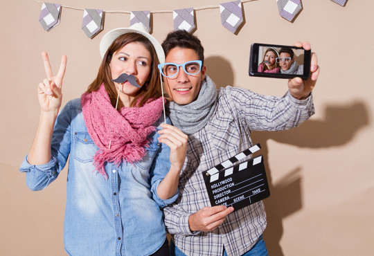 A boy and girl posing for selfie with fake mustache and fake glasses