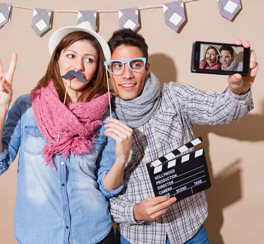 A boy and girl posing for selfie with fake mustache and fake glasses
