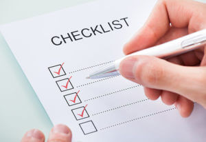 A person holding a pen checking off box on checklist