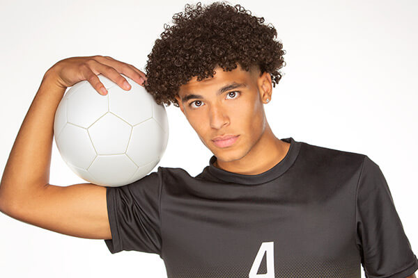A guy wearing a black jersey holding a white soccer ball