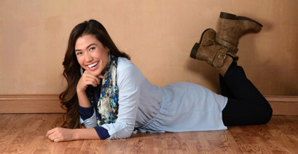 A girl smiling wearing blue dress laying on floor