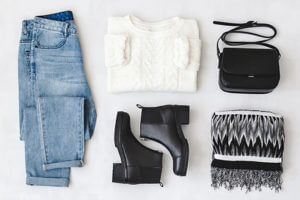 Jeans, white sweater, black boots, black purse, and black and white scarf