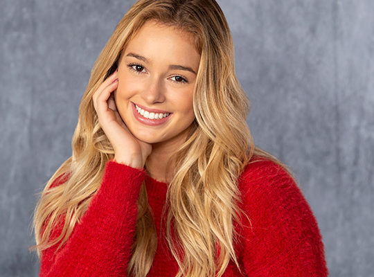 A girl smiling wearing a red sweater