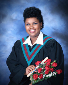 A girl smiling wearing a black graduation gown