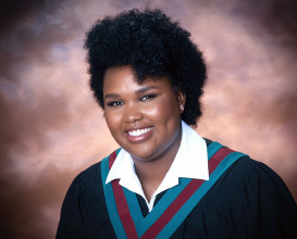 A girl smiling wearing a black graduation gown