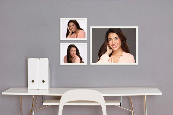 Framed senior portraits of girl hanging on wall in front of white desk